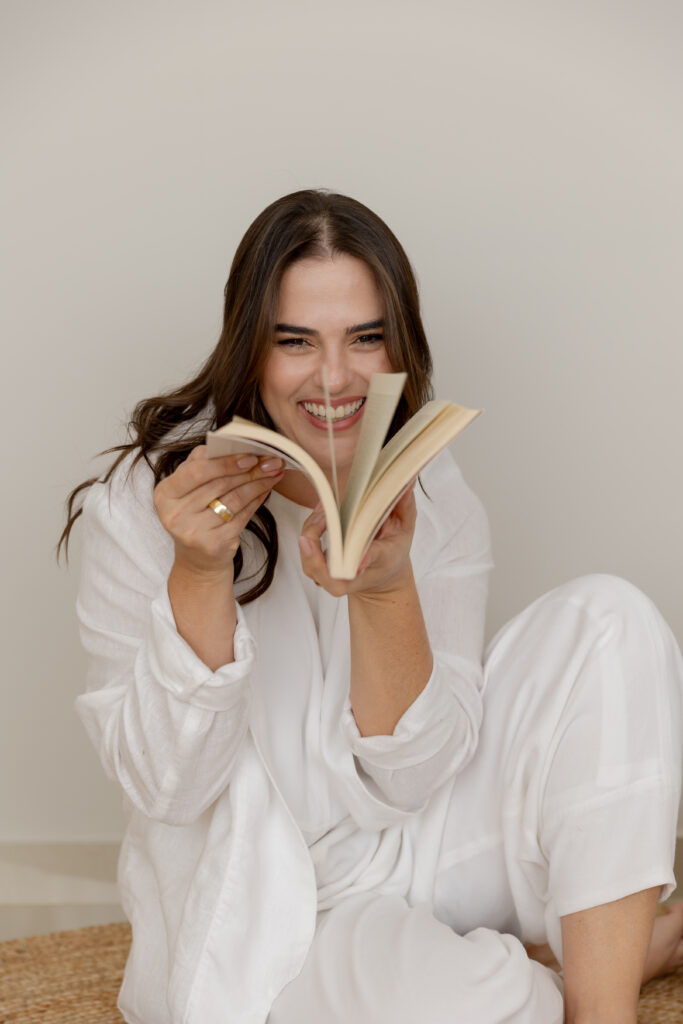 Thiara Palmieri, autora do livro Comunicadamente, segurando um livro aberto